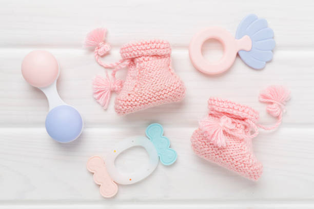 istock Pink baby booties and rattles on wooden background, top view 2200706830