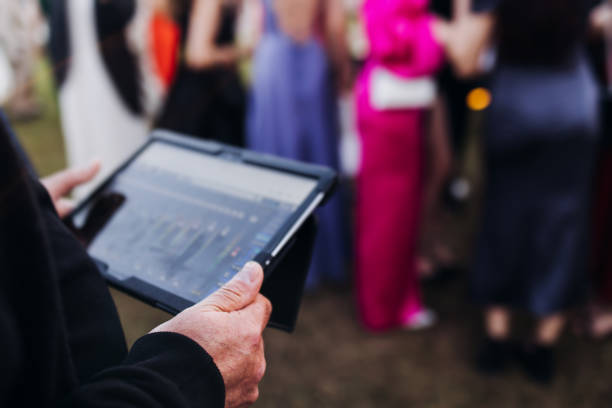 View of lighting technician with tablet, operator controlling sound and light during live event concert on stage show broadcast, technician with professional equipment, working on mixing console