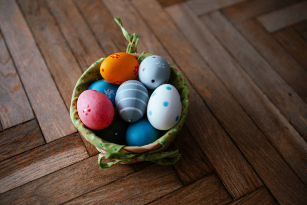 Decorative basket holds vibrant Easter eggs on rustic wooden flooring.