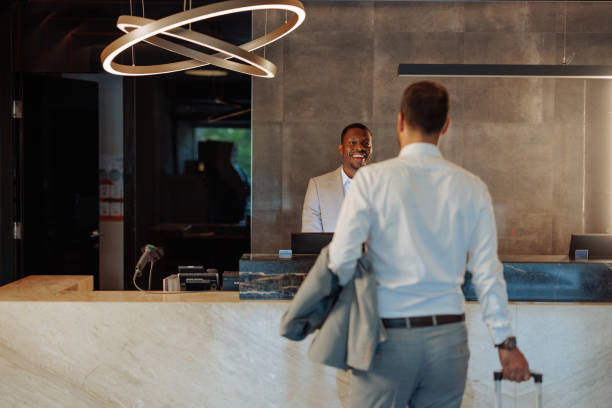 Businessman arriving at a hotel, checking in at the reception desk while engaging in a friendly conversation with the receptionist