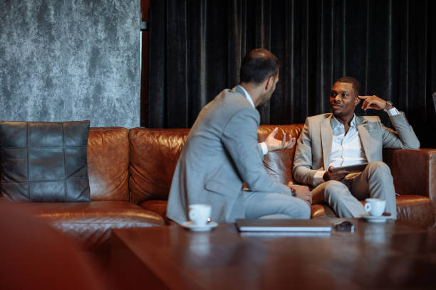 istock Two businessmen discussing work while sitting on a leather sofa in a luxurious hotel lobby 2200713339