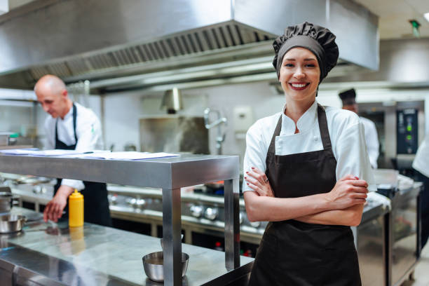istock Confident female chef smiling with arms crossed in a restaurant kitchen 2200713351