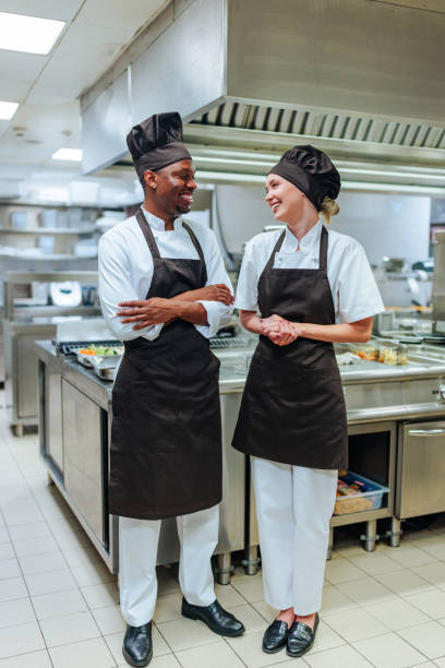istock Two chefs talking and smiling in a professional kitchen 2200713431