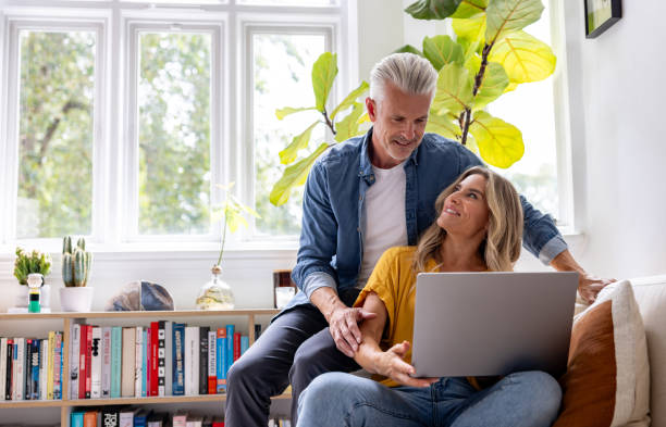 istock Happy couple using their laptop at home and smiling 2200718735