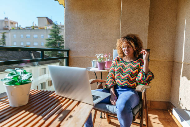 istock Woman looking at laptop on sunny balcony 2200721083