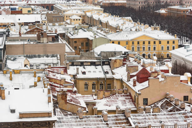 A low-rise apartment building set in a snowy winter landscape, featuring snow-covered rooftops and frosted windows, encircled by bare trees and a crisp, wintry ambiance