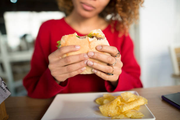 Woman holding sandwich at a restaurant table with potato chips