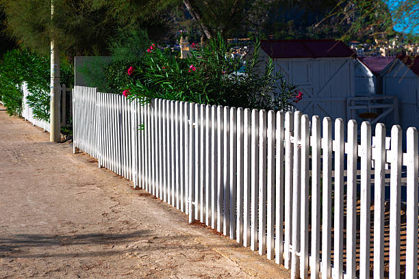 istock White picket fence running alongside a dirt path 2200722550
