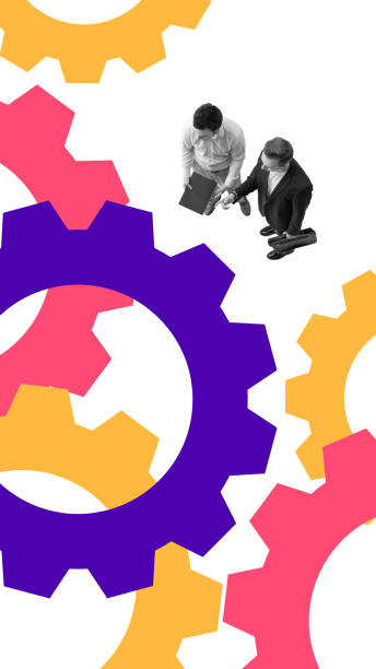 istock Two businessmen shaking hands while standing near large colorful gears, representing partnership, collaboration, and structured workflow 2200729286