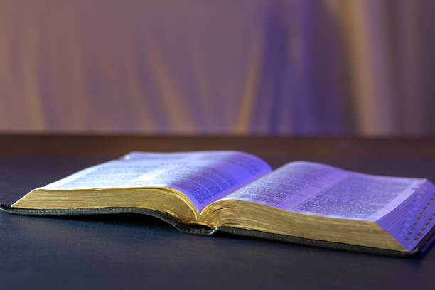 Open Holy Bible on the table. Religion concept. Bible on black background. High quality photo. Worshiping God, praying, and reading the Bible at home.
