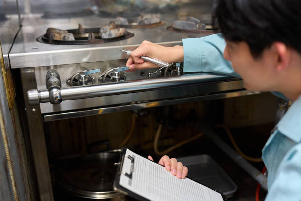 A man checking a gas stove at a restaurant stock photo