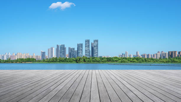 istock Empty wooden viewing platform with modern city waterfront skyline and sunny blue sky background 2200742627
