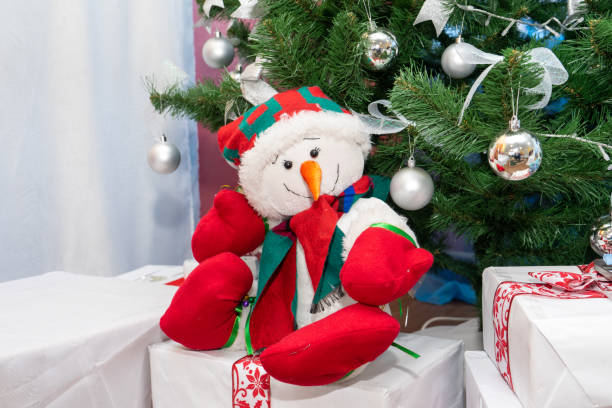 istock A cheerful snowman sits on gifts under the Christmas tree 2200743488