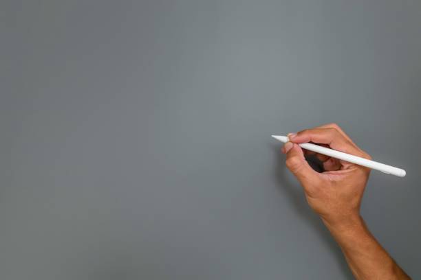 istock Hand holding a pencil or pen to write something on a gray background 2200746685