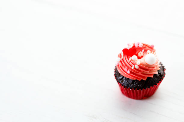 Chocolate cupcake with pink color buttercream in red present box on white wooden background. Sweet and love concept. Happy Valentines day concept.