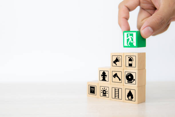 istock Close-up hand choose wooden toy blocks stacked with door exit sing icon with fire extinguisher and fire protection symbol for safety prevent and protect accident of emergency and rescue. 2200755555