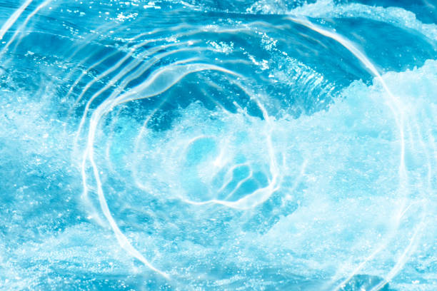 Blue water with ripples on the surface. Defocus blurred transparent blue colored clear calm water surface texture with splashes and bubbles. Water waves with shining pattern texture background.