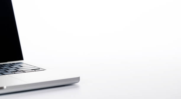 Closeup of an office table featuring a sleek laptop on a clean white surface with ample copy space, presented in high-key lighting for a minimalistic and professional vibe