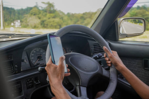 istock Image of texting while driving / dangerous and risky behavior with smartphone and steering wheel 2200761322