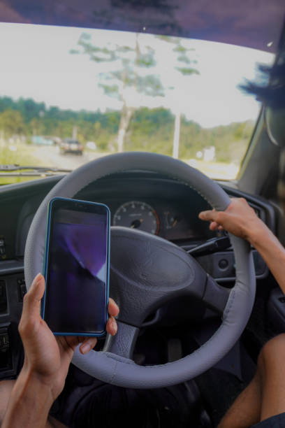 istock Image of risky texting while driving / dangerous distracted driving with smartphone and steering wheel 2200761324
