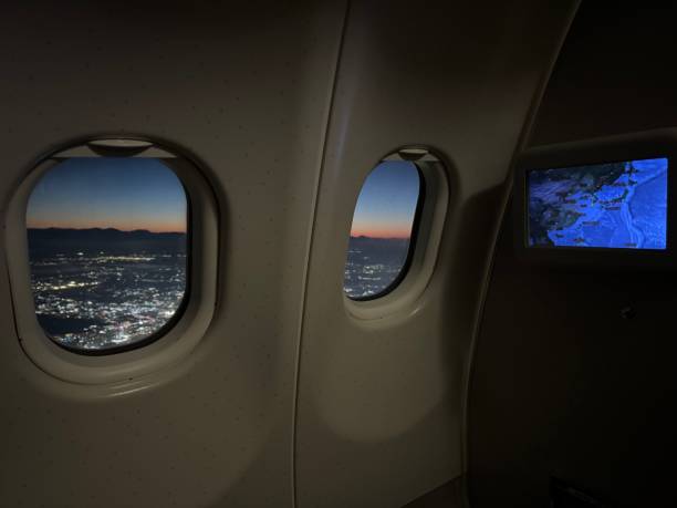 istock Sunset view from inside a plane with brightly lit city 2200761452
