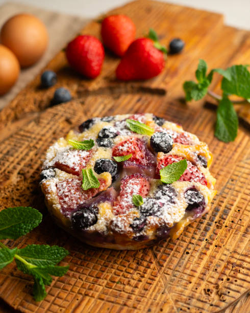 Delicious sweet clafoutis tart with blueberries and strawberries baked using a traditional French recipe.