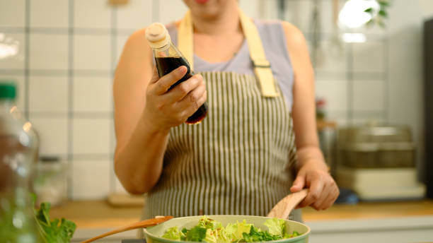 istock Woman preparing a healthy meal in a kitchen, adding soy sauce into a pan 2200768410