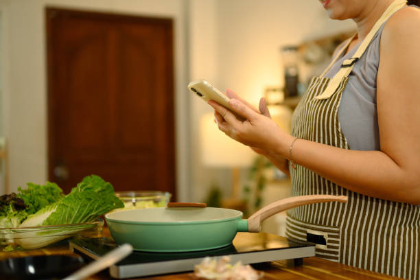 istock Middle aged woman checking a recipe on her mobile phone while cooking in the kitchen 2200768426