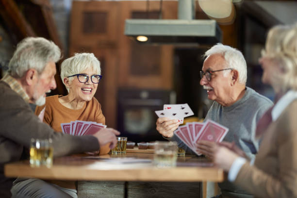 istock Happy senior friends enjoying while playing cards at home. 2200771614