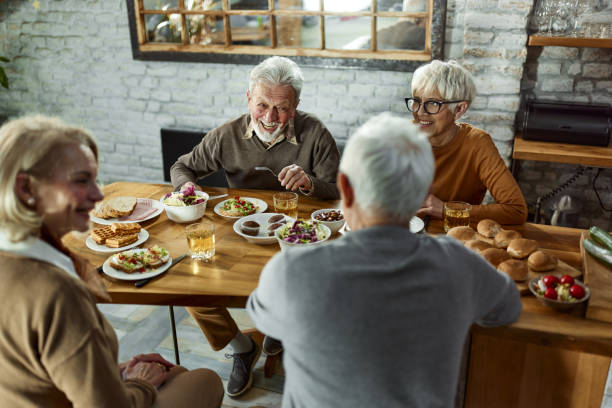 istock Happy mature couples enjoying in conversation during a meal at dining table. 2200771684