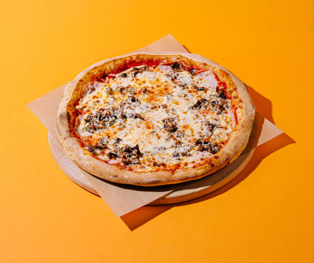 istock Freshly made pizza with a golden crust on an orange background ready to be enjoyed 2200772319