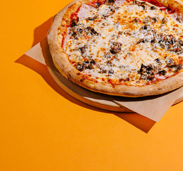 istock Freshly made pizza with a golden crust on an orange background ready to be enjoyed 2200772325