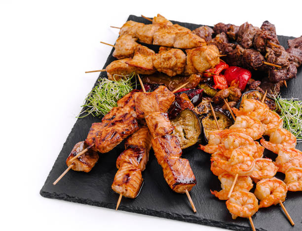 istock Grilled skewers featuring shrimp, beef, and chicken served on a slate platter with vegetables 2200772543