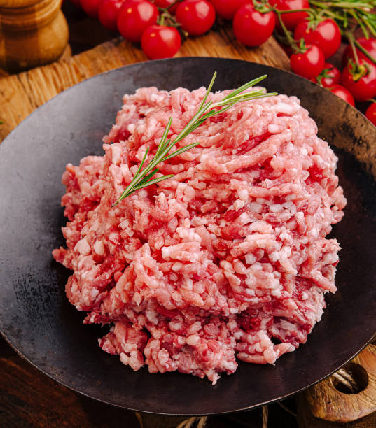 istock Freshly minced meat on a wooden table surrounded by spices and tomatoes ready for cooking 2200773495