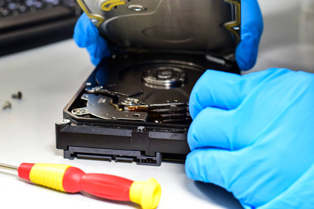 istock Computer technician wearing gloves with a screwdriver Dismantling and repairing hard disks on a work desk 2200777018