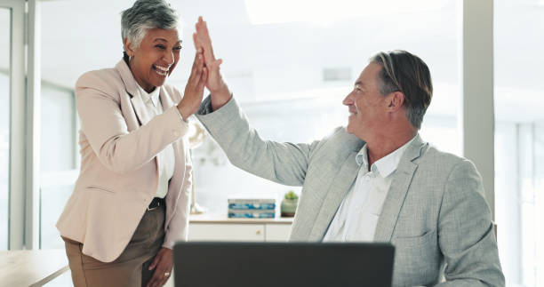 istock Mature, happy or business people with high five for teamwork, winning or celebration at office. Senior man, woman or colleagues with smile or touch for good job, achievement or promotion at workplace 2200778876