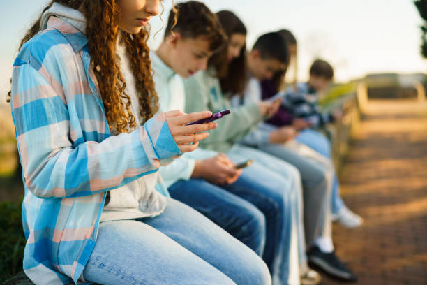 istock Children sitting in a row and using mobile phones 2200784930