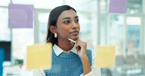 istock Thinking, glass wall and businesswoman with creative planning with notes in office for project. Brainstorming, board and female event designer working on startup ideas with research in workplace. 2200785712