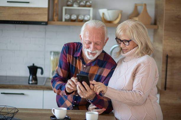 istock Senior couple using phone and reading online news while drinking coffee in the kitchen 2200785927