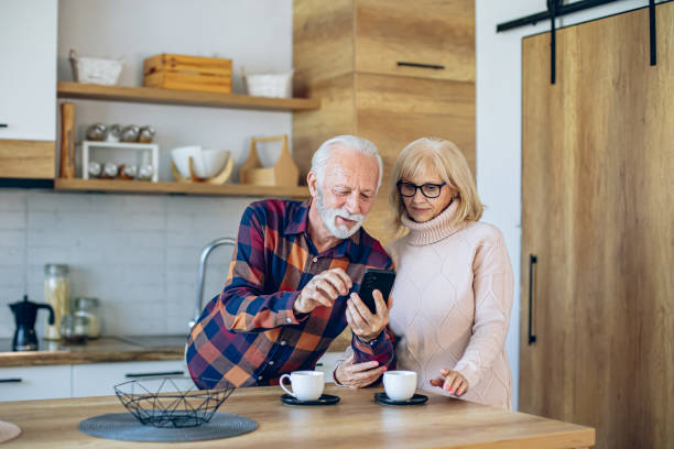 istock Senior couple using phone while relaxing with coffee in kitchen 2200786075