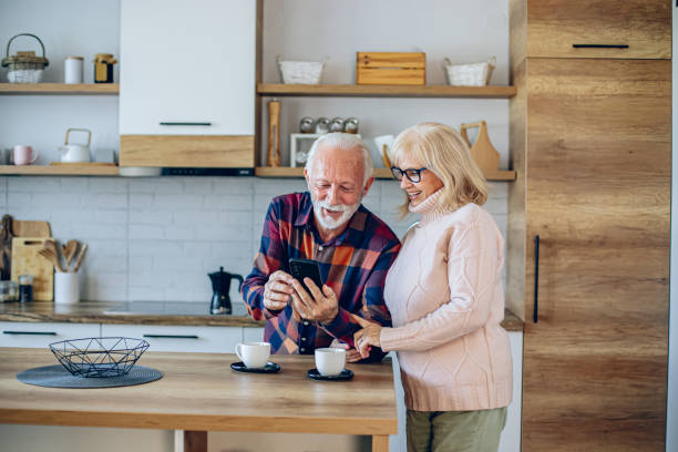 istock Senior couple using phone while relaxing with coffee in kitchen 2200786124