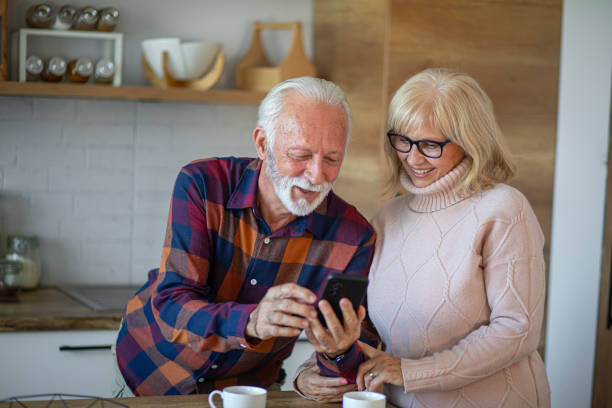 istock Senior couple using phone while relaxing with coffee in kitchen 2200786179
