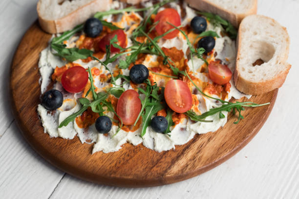 Butter board, butter with herbs topping and baguette bread slices on table, close up