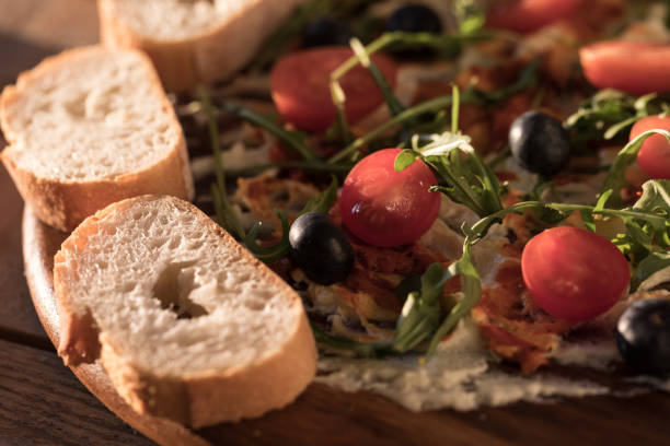 Butter board, butter with herbs topping and baguette bread slices on table, close up