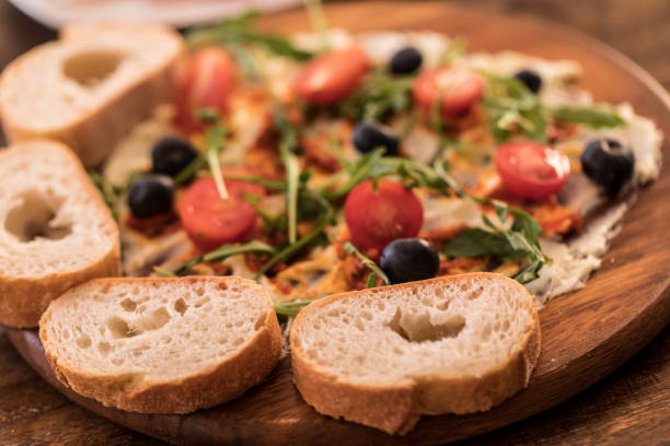 Butter board, butter with herbs topping and baguette bread slices on table, close up