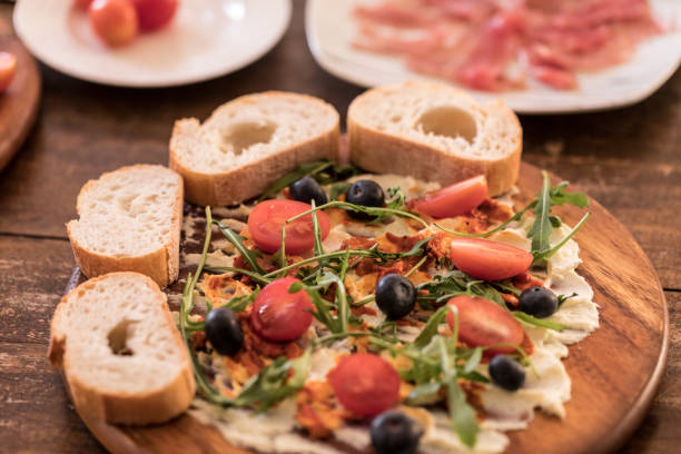 Butter board, butter with herbs topping and baguette bread slices on table, close up