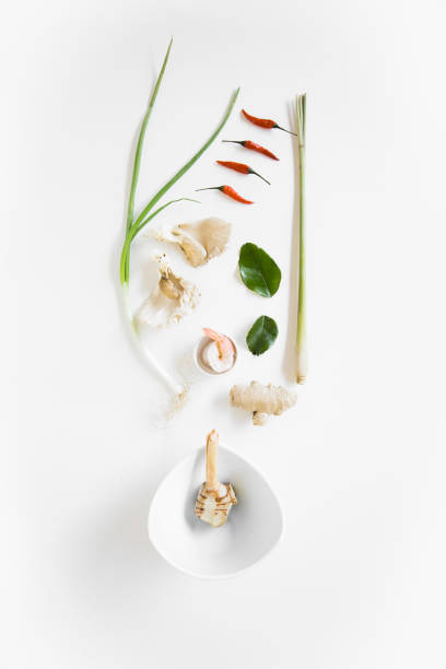 This image presents a beautifully arranged selection of fresh Thai herbs and spices on a clean white background. The ingredients include lemongrass, galangal, kaffir lime leaves, red chili, garlic, shallots, and spring onions—key components in traditional Thai cooking. Their vibrant colors and natural textures highlight the freshness and aromatic qualities essential in Thai cuisine. Perfect for restaurant branding, food photography, or culinary storytelling, this image captures the essence of authentic Thai flavors.