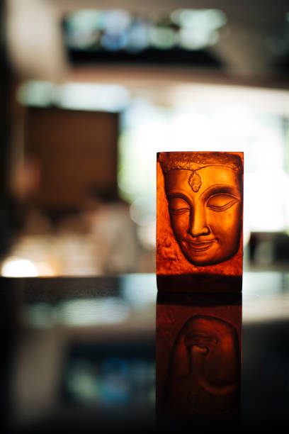 istock Illuminated Buddha face candle holder with a warm glow, Placed on a reflective surface in a serene ambiance, Spiritual and artistic decor for Thai restaurant or meditation space 2200792218