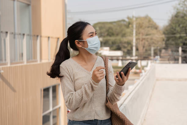 istock Diverse woman in a mask using a smartphone outdoors in an urban environment. 2200794647