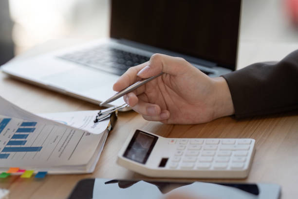 istock Business professional analyzing financial data and project plans with calculator and laptop in modern office. 2200798509